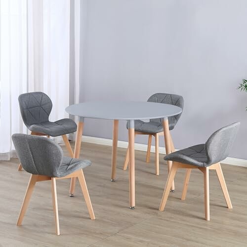 Modern dining set with a round table and four gray upholstered chairs.