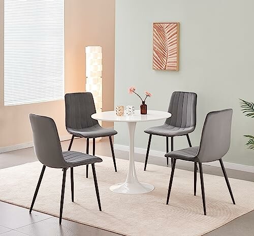 Modern dining set with round table and four gray chairs.