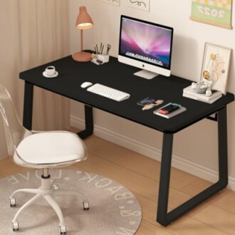 A modern home office desk with a computer, lamp, chair, and decor.
